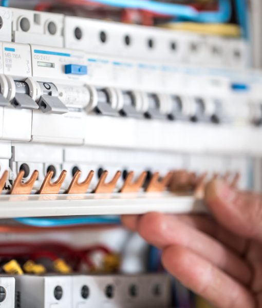 man-electrical-technician-working-switchboard-with-fuses-installation-connection-electrical-equipment-close-up